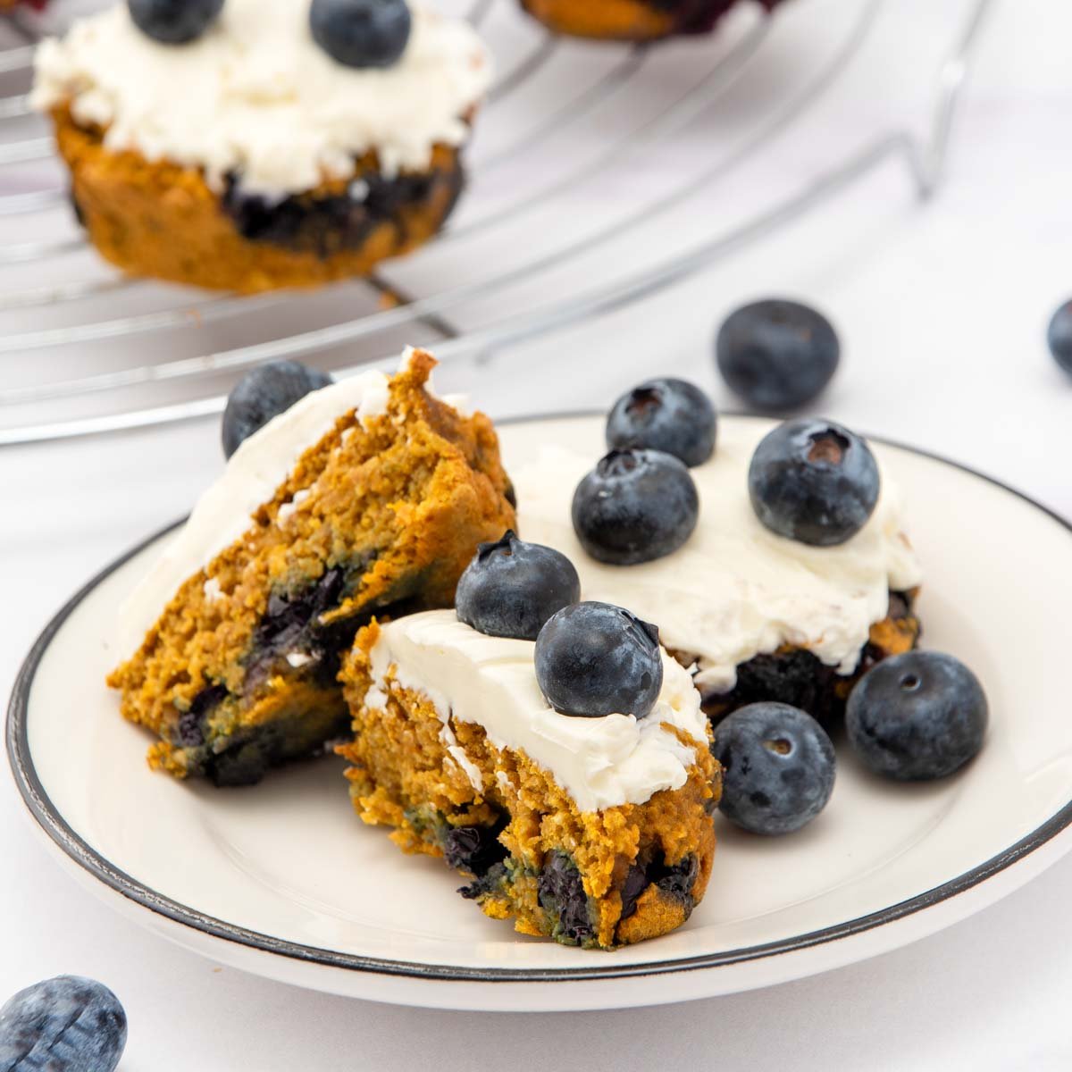 Blueberry pupcakes with white frosting and fresh blueberries on a plate