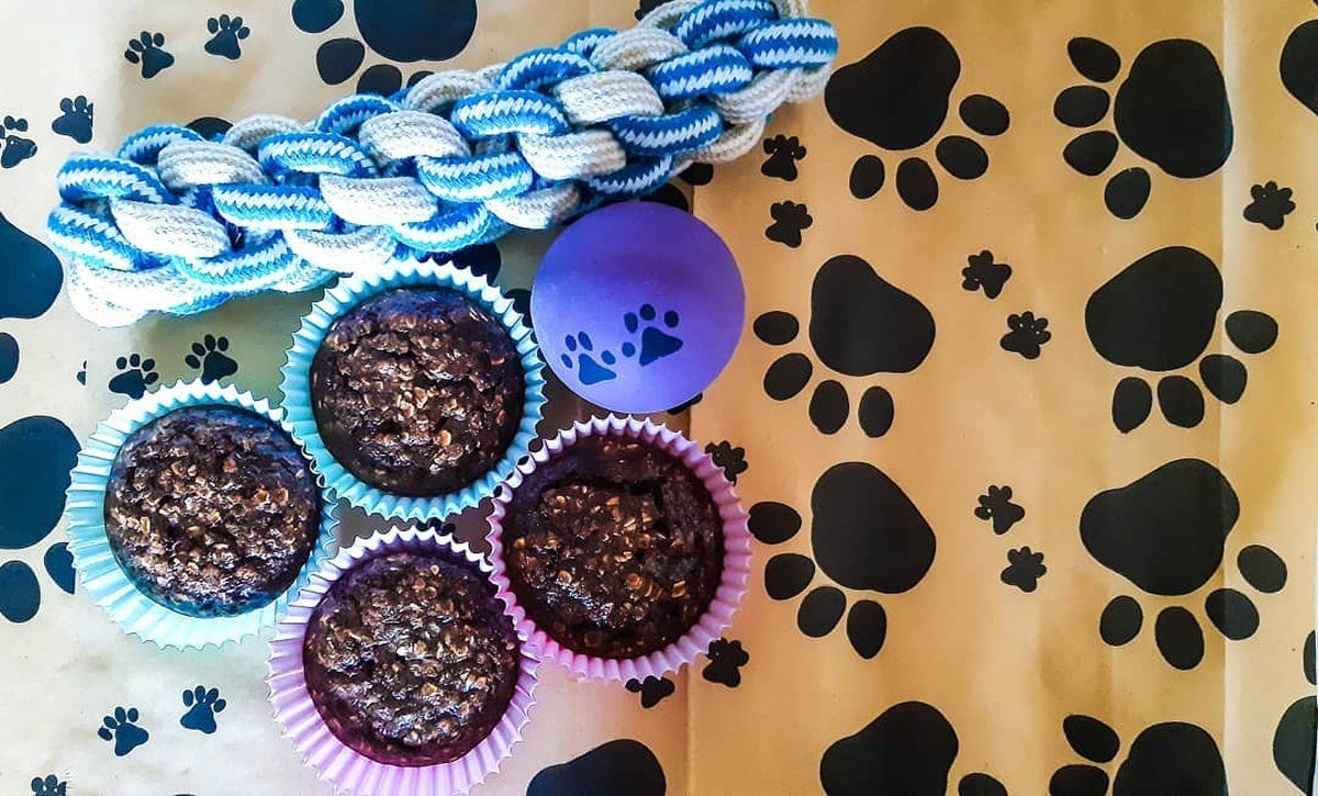Dark savory liver pupcakes in paper liners with a rope toy and paw ball