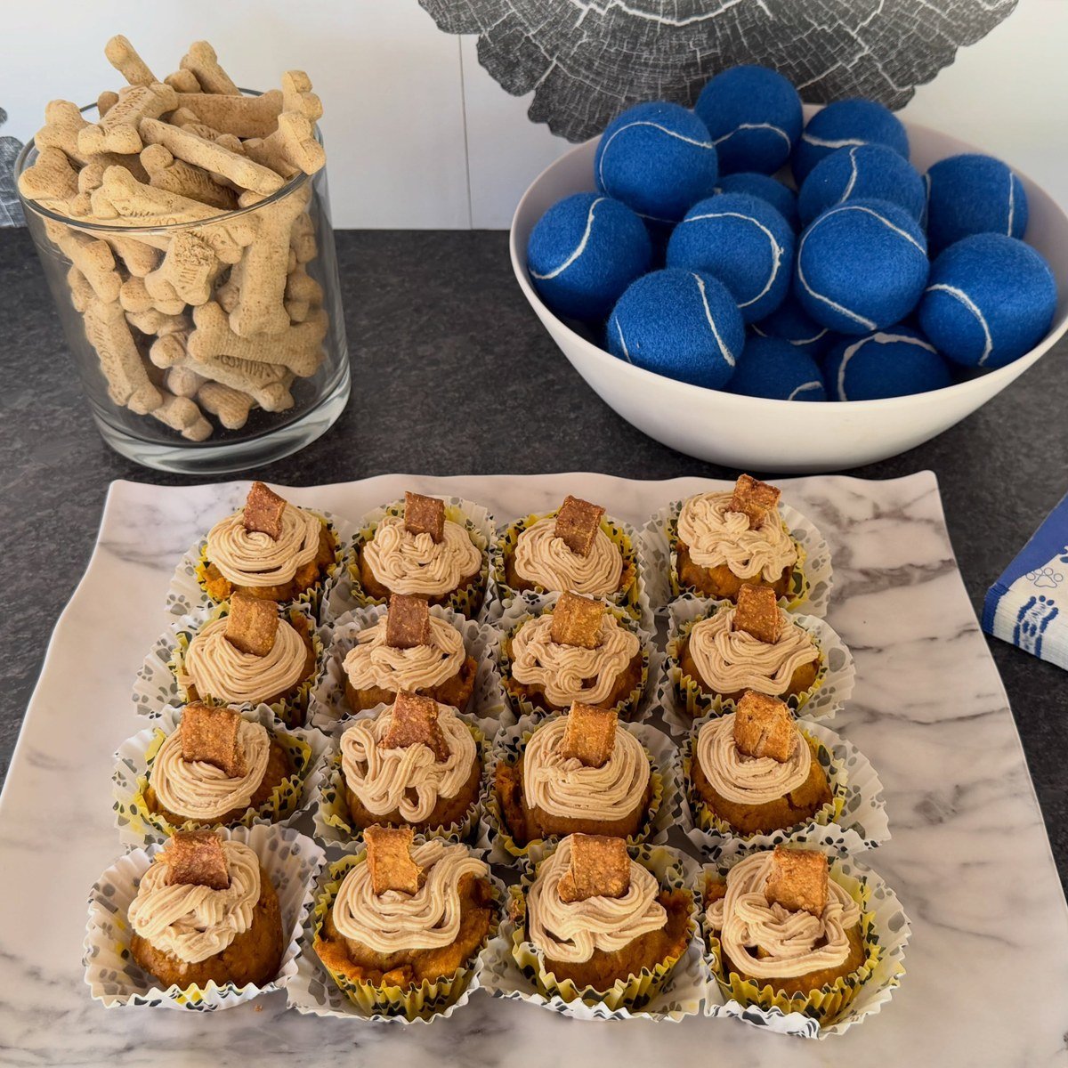 Frosted grain-free pupcakes in paw-print liners topped with biscuit pieces