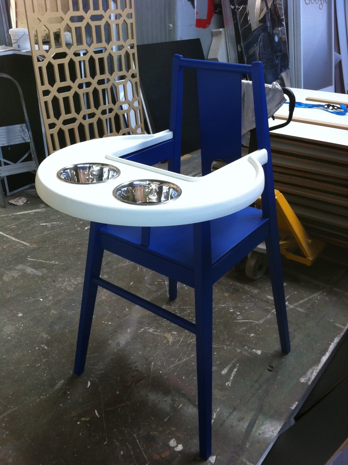 Custom blue wooden feeder styled like an IKEA children's high chair with tray holding two steel bowls. No readable text.