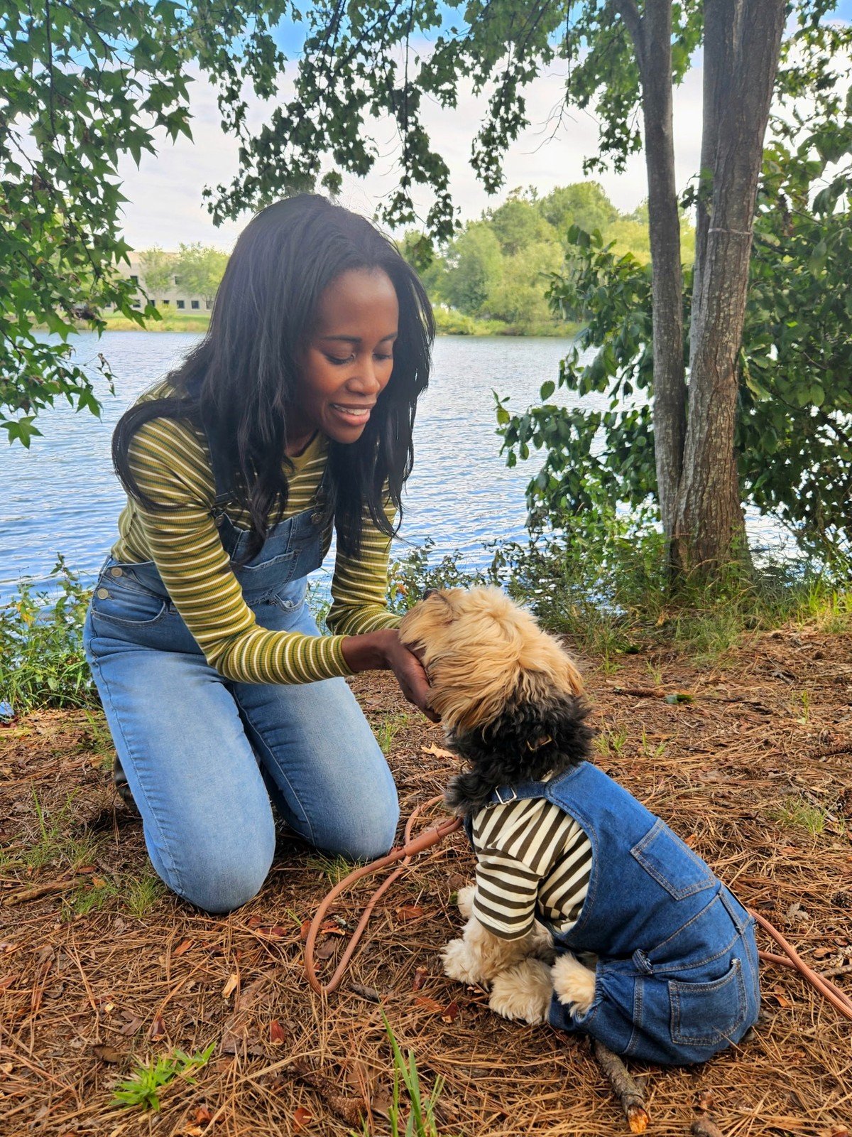 Woman and dog wearing coordinated striped tops and overalls; no text