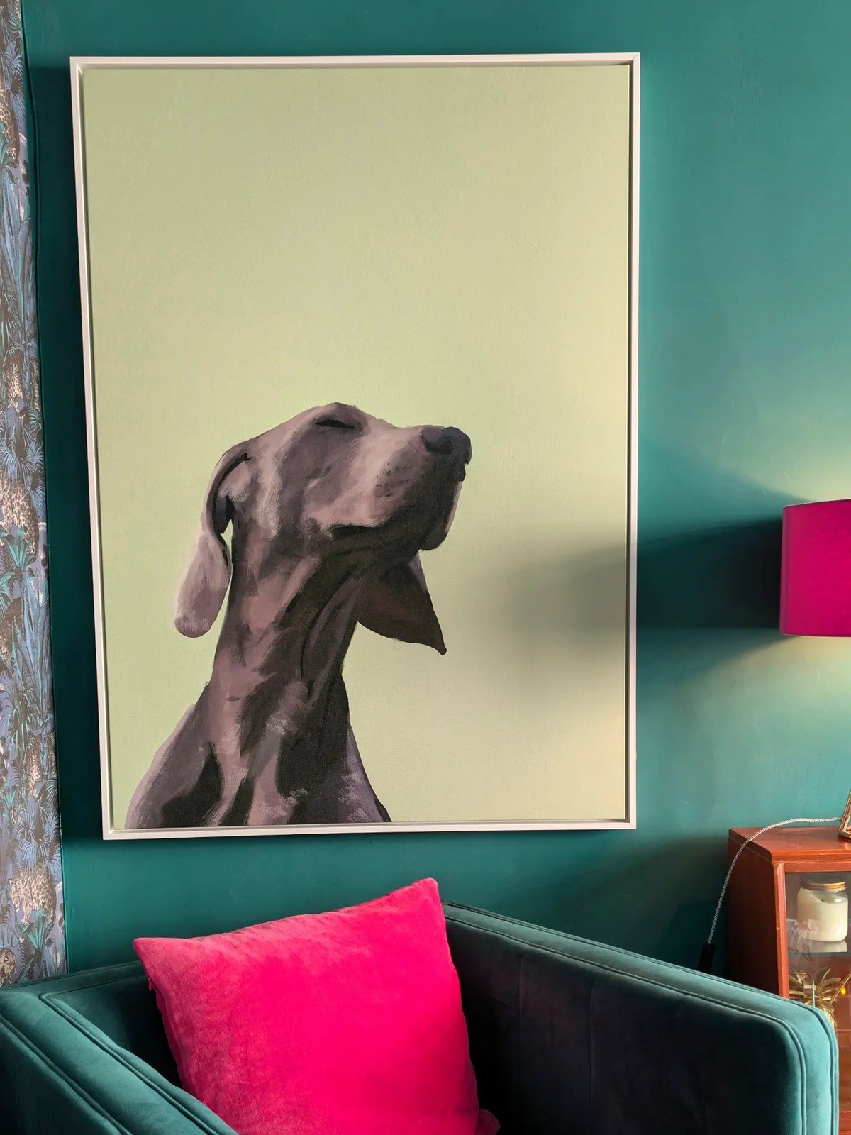 Teal office wall with a large framed canvas painting of a gray Weimaraner; dark teal armchair below.