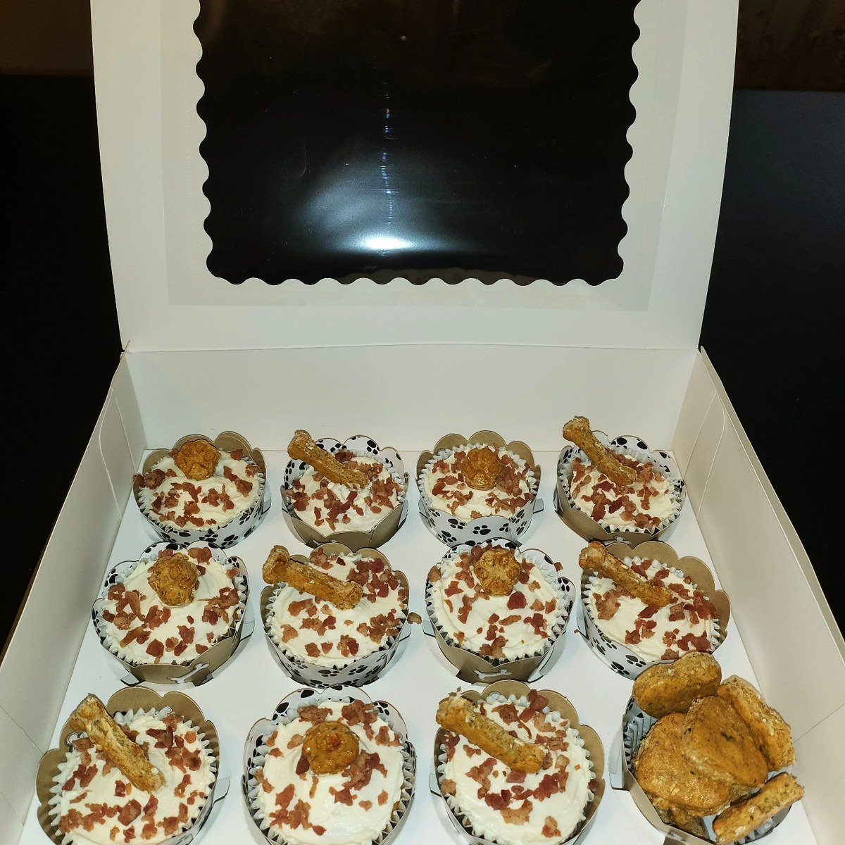 Box of pumpkin pupcakes with cream cheese frosting, bacon sprinkles, and bone-shaped cookie toppings