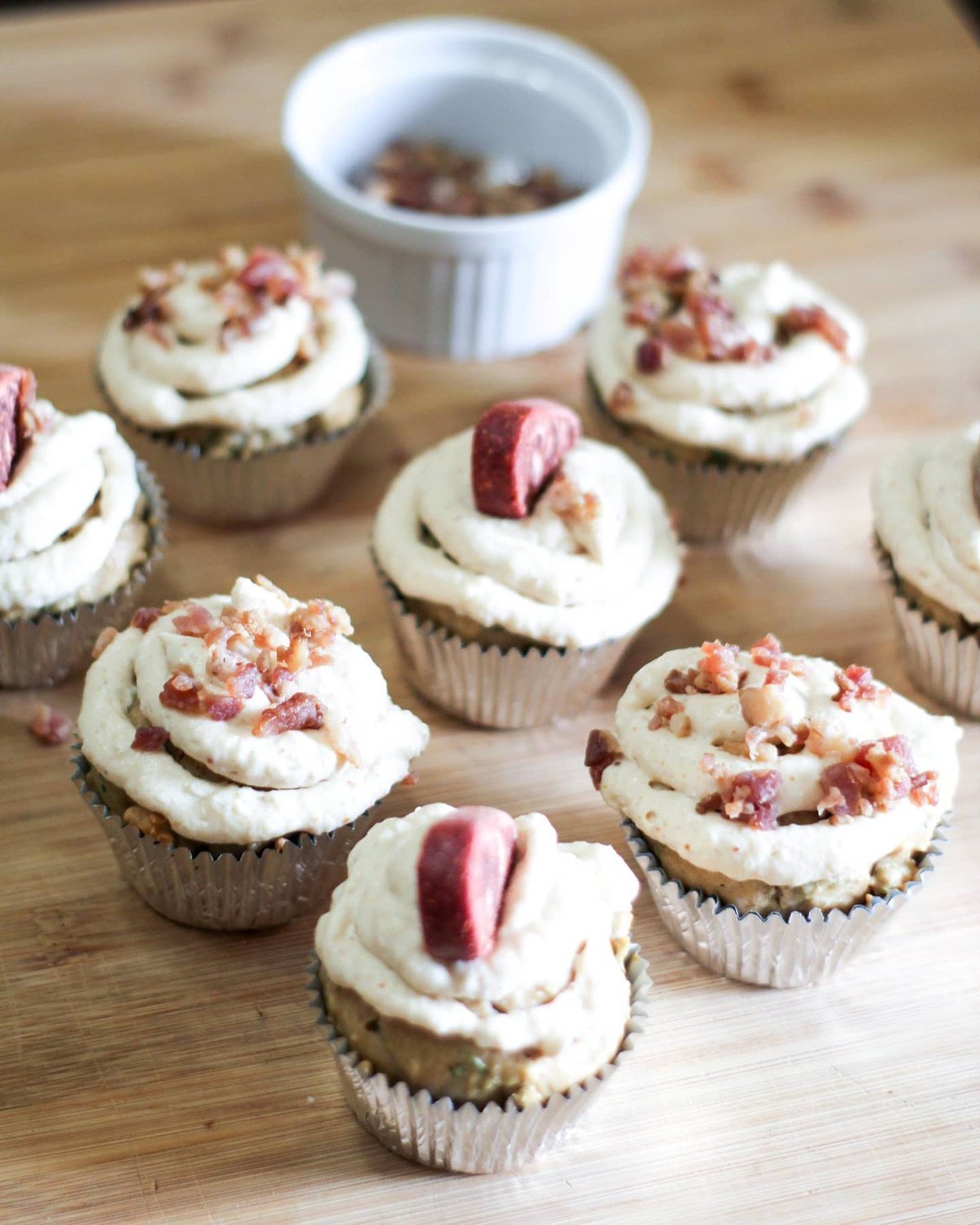 Savory pupcakes with cream frosting topped with bacon bits and sausage pieces