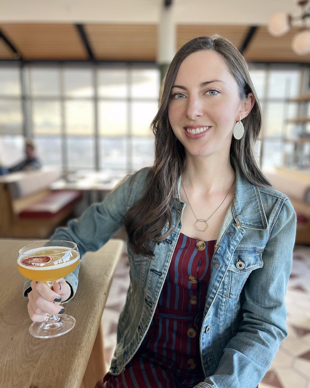 Woman holding a signature wedding cocktail coupe at a bar
